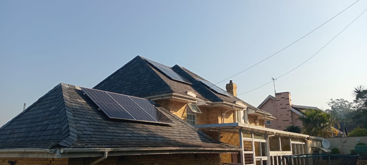 House with solar panels on the roof against a clear blue sky