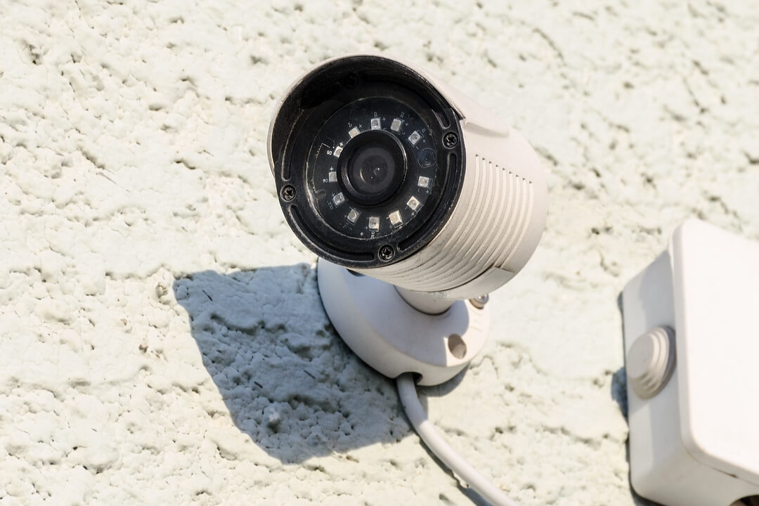 White security CCTV camera on a textured white surface