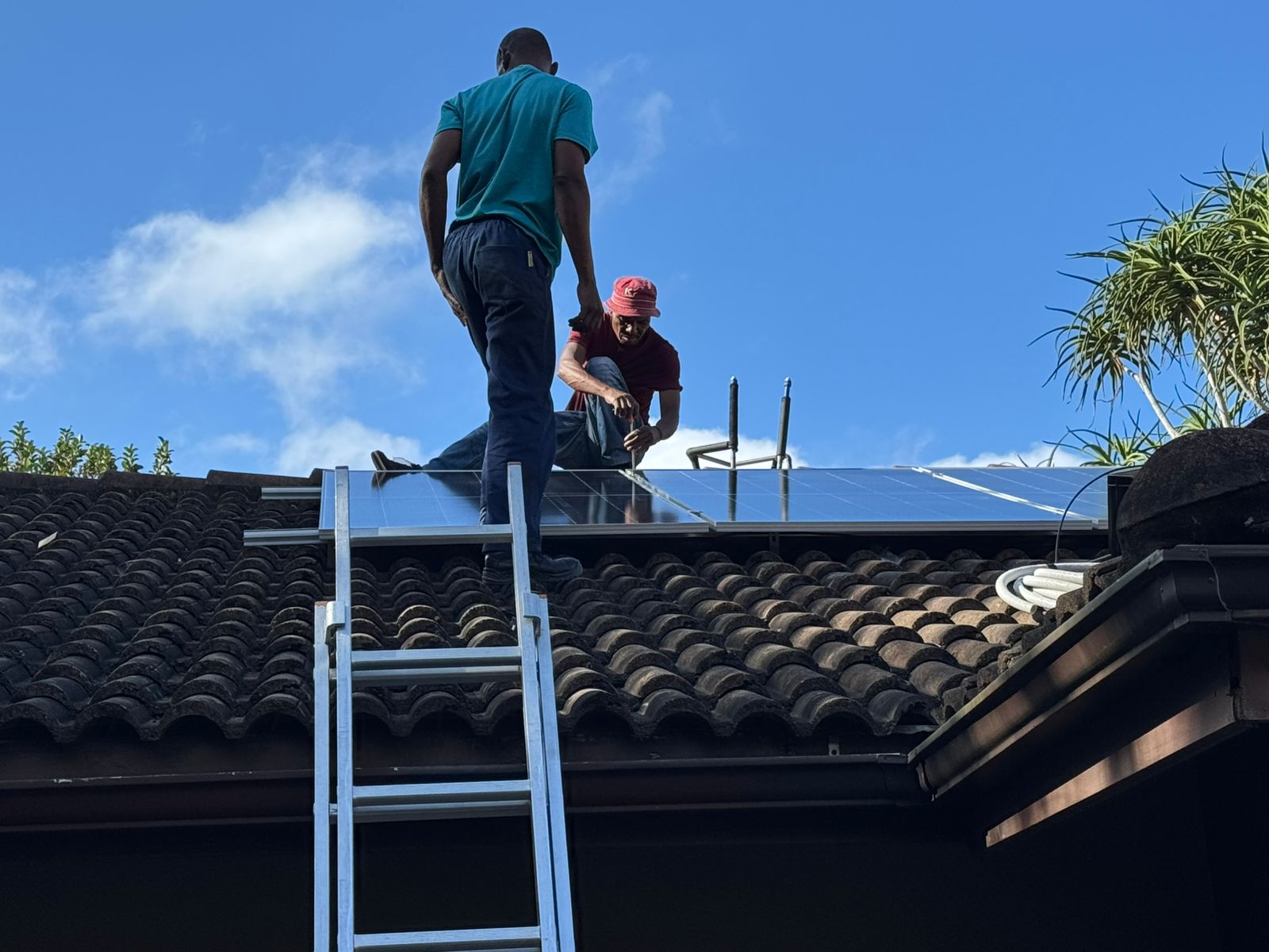 Qualified technicans installling solar panels on a roof for a client in Kloof